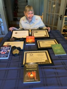 Linda sitting at a table showing her book awards